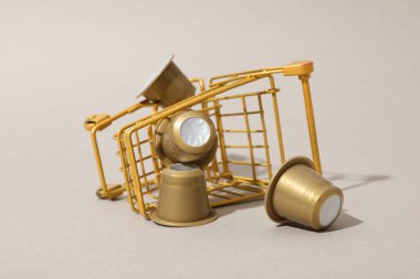 Bej arka planda alışveriş tepsisinde altın kahve kapsülleri, kapatın.