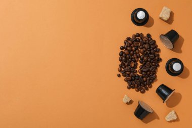 Kahve kapsülleri, kahve çekirdekleri ve kahverengi arka planda şeker, metin için boşluk
