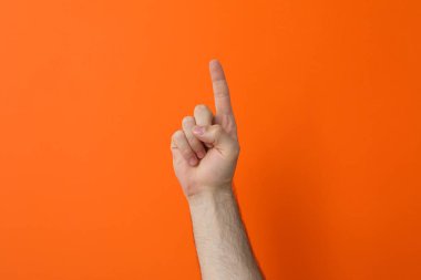 Turuncu arka planda işaret parmağı gösteren bir erkek el.