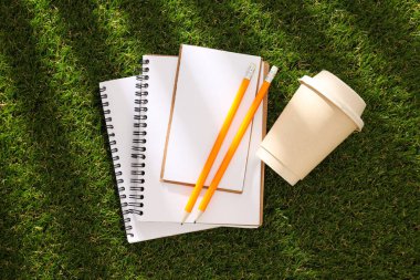 Çimlerin üzerinde kalem olan kağıt bir defter..