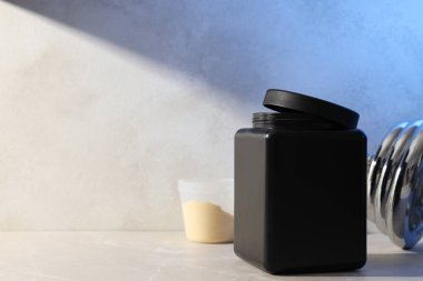 Siyah plastik kavanoz, pudra ve halterli ölçü kabı hafif arka planda, metin için boşluk