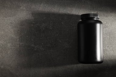 Koyu gri arkaplanda siyah plastik kavanoz, metin için boşluk