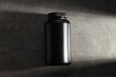 Koyu gri arka planda siyah plastik kavanoz, üst görünüm