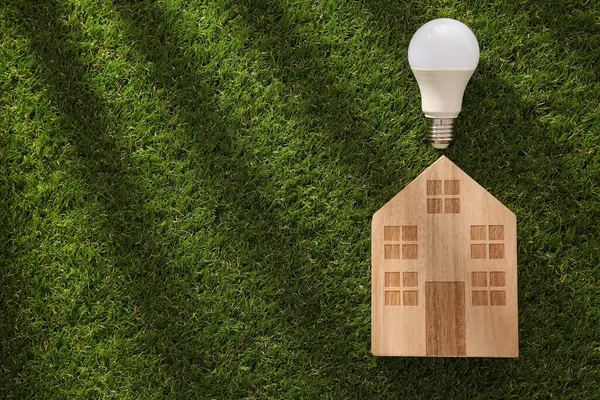 stock image A wooden house with a lamp on the grass.