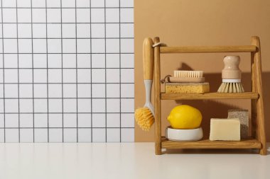 Fırçalar, süngerler, sabun ve limon ahşap rafta hafif arka planda, metin için boşluk