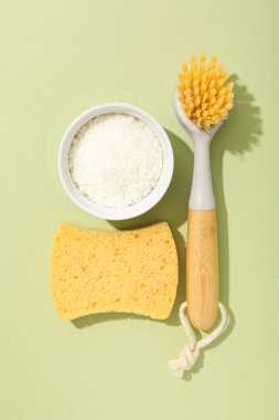 Yeşil arka planda fırçalar, süngerler ve soda, üst manzara.