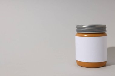 Gri arka planda etiketli kavanoza fıstık ezmesi..