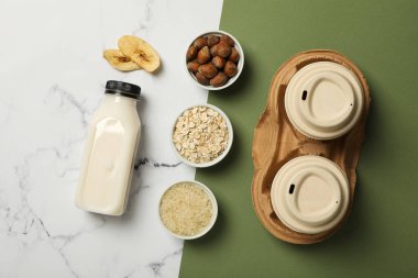 Alternatif süt, bitkisel malzemeler ve beyaz ve yeşil arka planda kağıt bardaklar.