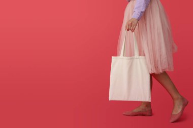 Pembe etekli, pembe arka planda pamuk çantalı bir kadın.