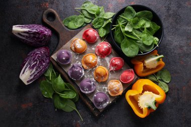 Mutfak tahtasındaki renkli hamur köfteleri ve pembe arka plandaki havlu, metin için yer