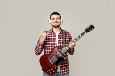 Kulaklıklı ve gitarlı çekici bir genç.