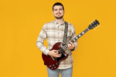 Elinde sarı bir arka planda gitar olan çekici bir genç.