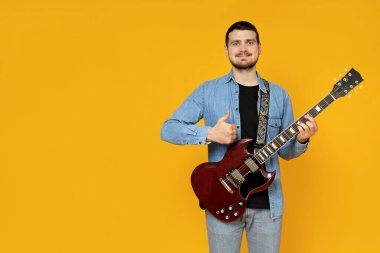 Elinde sarı bir arka planda gitar olan çekici bir genç.