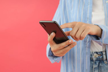 Çekici bir genç kız elinde bir akıllı telefon tutuyor.