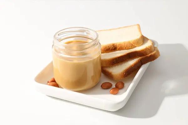 stock image Peanut paste in a glass jar, on a light background.