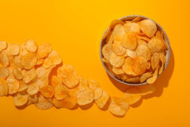 Sarı arka planda bir kasede patates cipsi