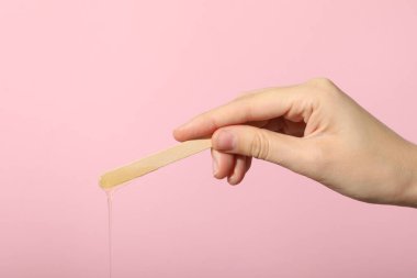 Pembe arka planda tüy dökmek için tahta bir çubuk.