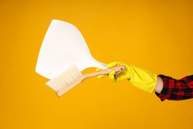 Turuncu arka planda kadın eldivenli fırça ve faraş