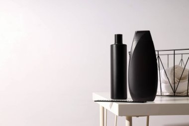 Erkek kozmetik ürünleri şişesi ve beyaz arka plandaki havlularla dolu sepet, metin için yer