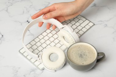 Kulaklıklı bir fincan kahve ve beyaz arka planda bir klavye.