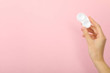 Pembe arka planda bir elde kontak lensler için bir konteyner