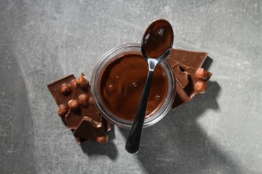 Kavanozda çikolata ezmesi ve gri arka planda çikolata.