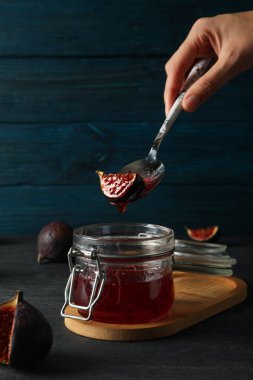 İncir, reçel kavanozu ve kaşık mavi ahşap arka planda.