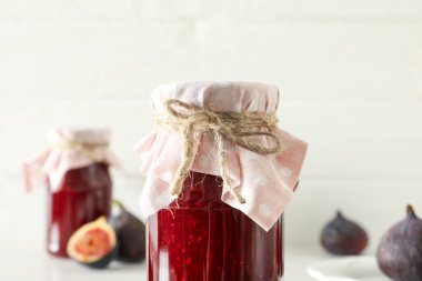 Beyaz arka planda incir ve kavanoz reçel, kapatın.