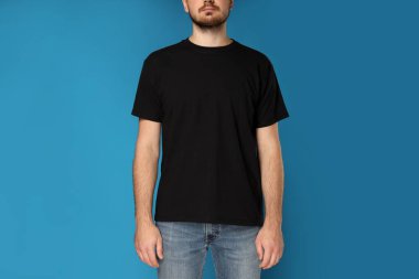 Mavi arka planda siyah tişörtlü genç bir adam.