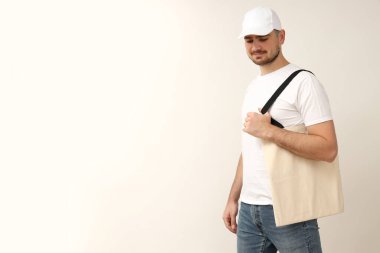 Beyaz tişörtlü, arka planda genç bir adam.