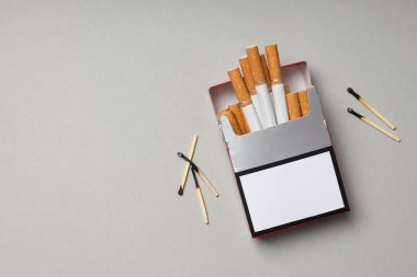 Hafif arka planda kibritleri olan bir paket sigara.