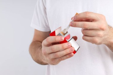 Bir paket sigara erkeğin elinde ve hafif bir arka planda.