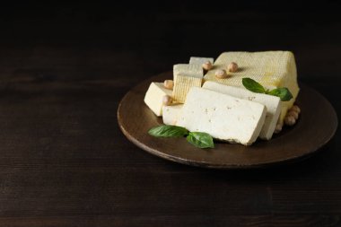 Koyu bir arka planda, tahta bir kasede tofu.