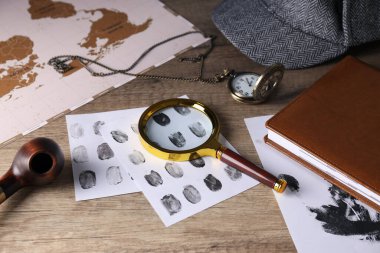 Üzerinde parmak izi, harita ve şapka olan büyüteç.