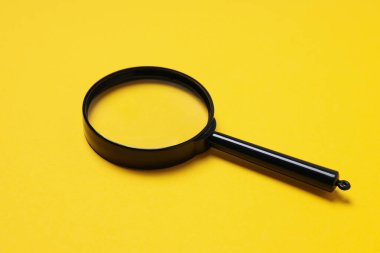 Sarı zemin üzerinde siyah çerçeveli bir büyüteç.