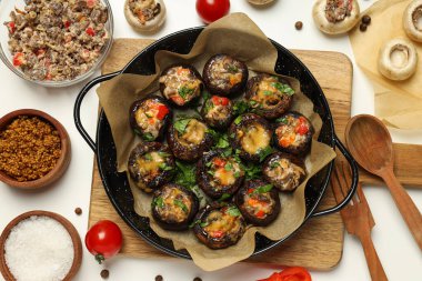 Kızartma tavasına doldurulmuş mantar ve beyaz arka planda malzemeler, üst manzara.