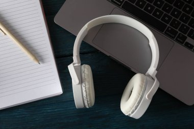 Mavi arka planda dizüstü bilgisayarı olan kulaklıklar.