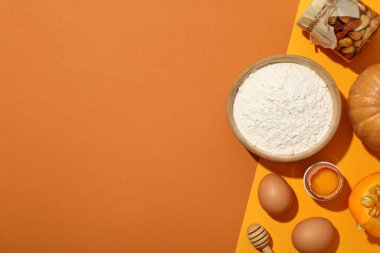 Turuncu arka planda fırın, balkabağı ve fındık malzemeleri, metin için boşluk