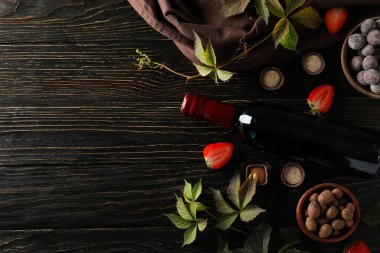 Koyu, ahşap bir masada çiçekli bir şişe şarap..