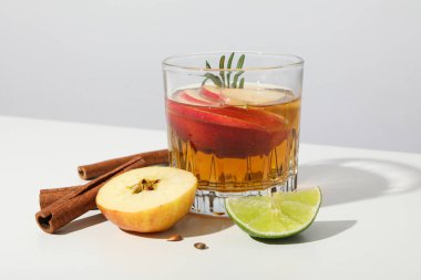 Elma şırası, tarçın çubukları, beyaz arka planda limon ve elma parçaları, kapatın.