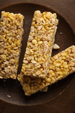 Koyu arkaplanda tahtadan bir kase içindeki granola çubukları