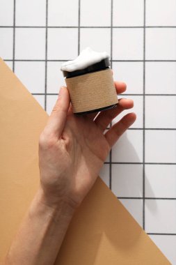 Elinde kozmetik kavanozu, arka planda, üst görünümde.