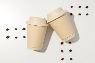 Kapaklı kağıt bardaklar ve kahve çekirdekleri.