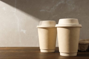 Tahta bir masada kapaklı kağıt bardaklar.