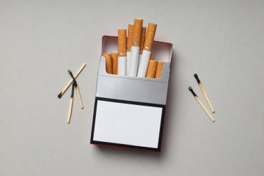 Hafif arka planda kibritleri olan bir paket sigara.