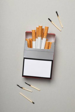 Hafif arka planda kibritleri olan bir paket sigara.