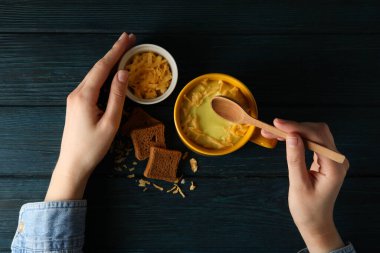 Tahta bir masada, sarı bir fincanda peynir çorbası.