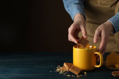 Tahta bir masada, sarı bir fincanda peynir çorbası.