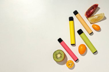 Beyaz arka planda taze meyveli elektronik sigaralar.