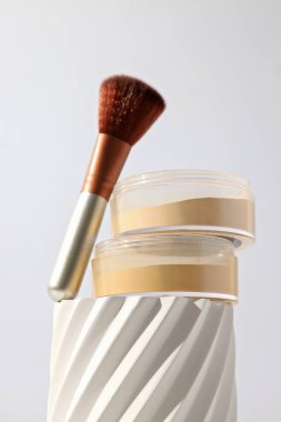 Hafif bir arka planda, fırçayla birlikte yüz pudrası.